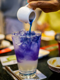 Close-up of hand pouring drink in glass