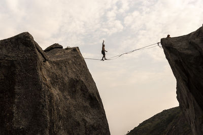 Low angle view of person on rock against sky