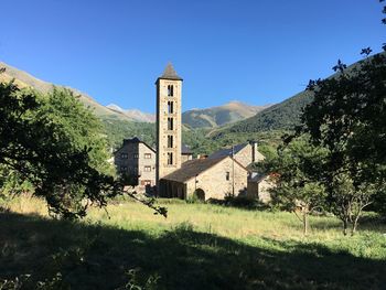 Church on field by buildings against clear blue sky