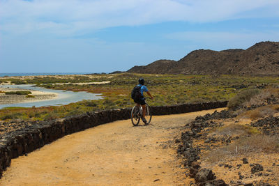 Rear view of man walking on mountain against sky