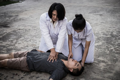 Nurse examining man lying outdoors