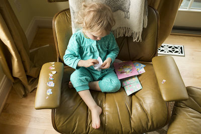 Overhead view of blonde girl putting stickers on tan chair