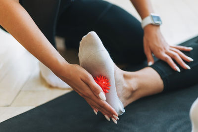 The trainer massages female feet with spiked ball, prevention of flat feet