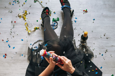 Young woman plus size body positive in black dress with firecracker and champagne at home party