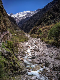 Scenic view of stream amidst mountains against sky