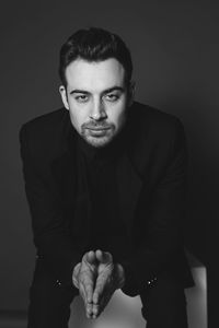 Portrait of young man standing against black background