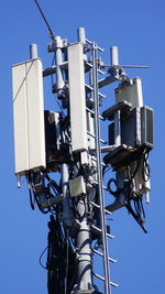 Low angle view of electrical tower against clear blue sky