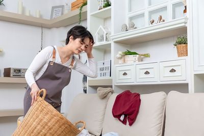 Side view of young woman sitting on bed at home