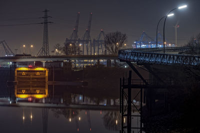 Illuminated bridge over river against sky at night