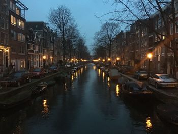 Canal amidst illuminated city against sky at night