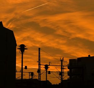 Low angle view of silhouette buildings against orange sky