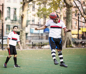 Man looking at soccer player hitting ball with head at field