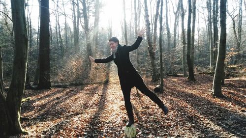 Woman standing on tree trunk in forest