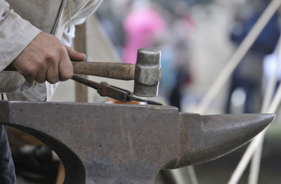 Midsection of man working on metal in workshop