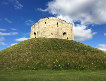 Low angle view of clifford tower on hill against cloudy sky 