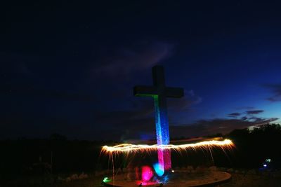 Illuminated cross against sky at night