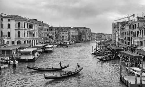 Boats moored at canal against buildings in city