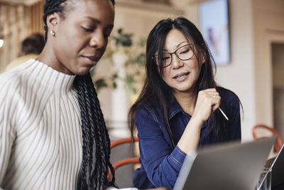 Businesswoman discussing with female colleague over laptop at coworking office