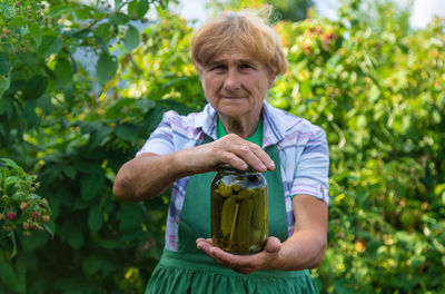 Portrait of senior woman holding pickle jar