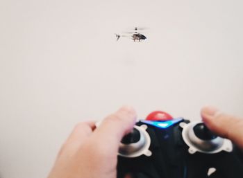 Cropped hands of person holding remote control against toy helicopter