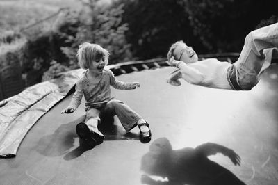 Full length of brother and sister playing on trampoline 