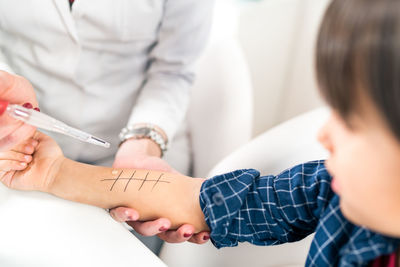 Close-up of doctor performing immunology therapy on hand of boy 