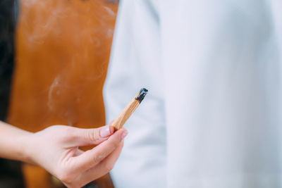 Peaceful woman sitting and meditating, spiritual coach with palo santo stick