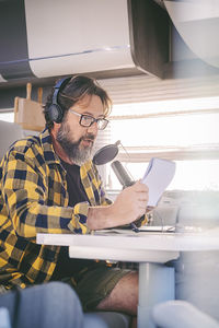 Side view of man using mobile phone while sitting at home