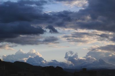 Silhouette of buildings against cloudy sky