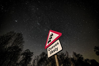 Low angle view of road sign against sky at night