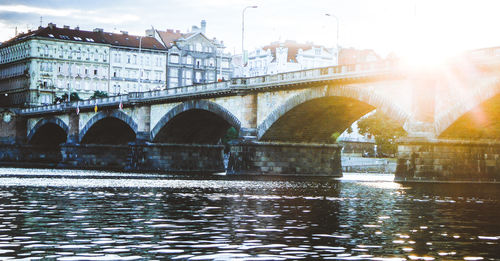 Bridge over river in city against sky