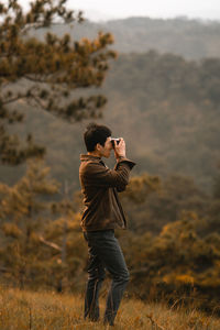 Side view of man photographing on field