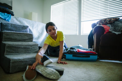 Tween girl reaches for shoes to pack in her suitcase