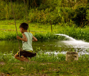 Rear view of boy swinging in park