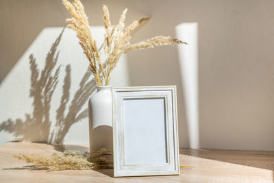 Portrait frame mock up with dried flowers on wooden table