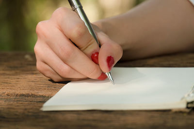 Midsection of woman holding paper with text on table