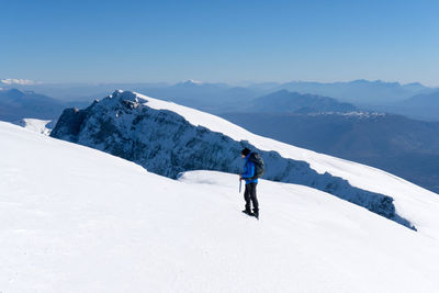 Man skiing on snowcapped mountains against sky