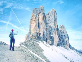 Rear view of man standing on mountain against sky