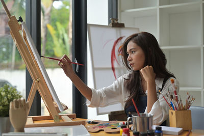 Young woman looking away while sitting on table