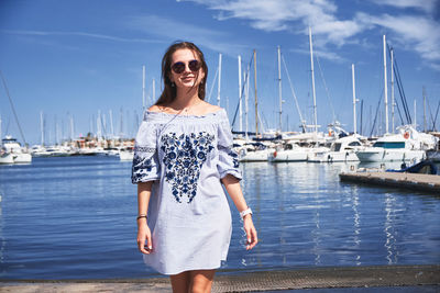 Portrait of smiling young woman standing at harbor