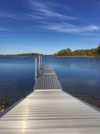 Empty wooden jetty leading to calm blue lake