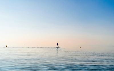 Man paddleboarding in sea against sky