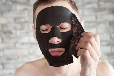 Close-up of man removing facial mask at home