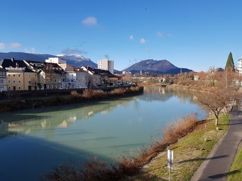 Scenic view of lake by buildings against blue sky