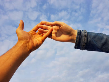 Low angle view of people hand against sky