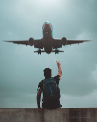 Rear view of man sitting on airplane against sky