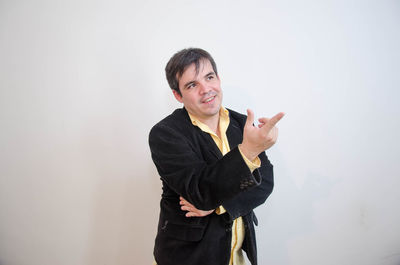 Businessman pointing while looking away against white background