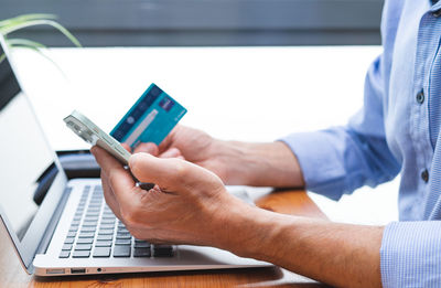 Midsection of man using mobile phone