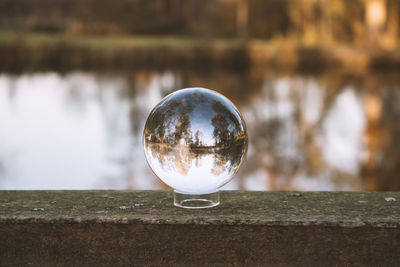 Close-up of crystal ball on railing against lake