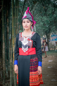 Portrait of woman standing against trees